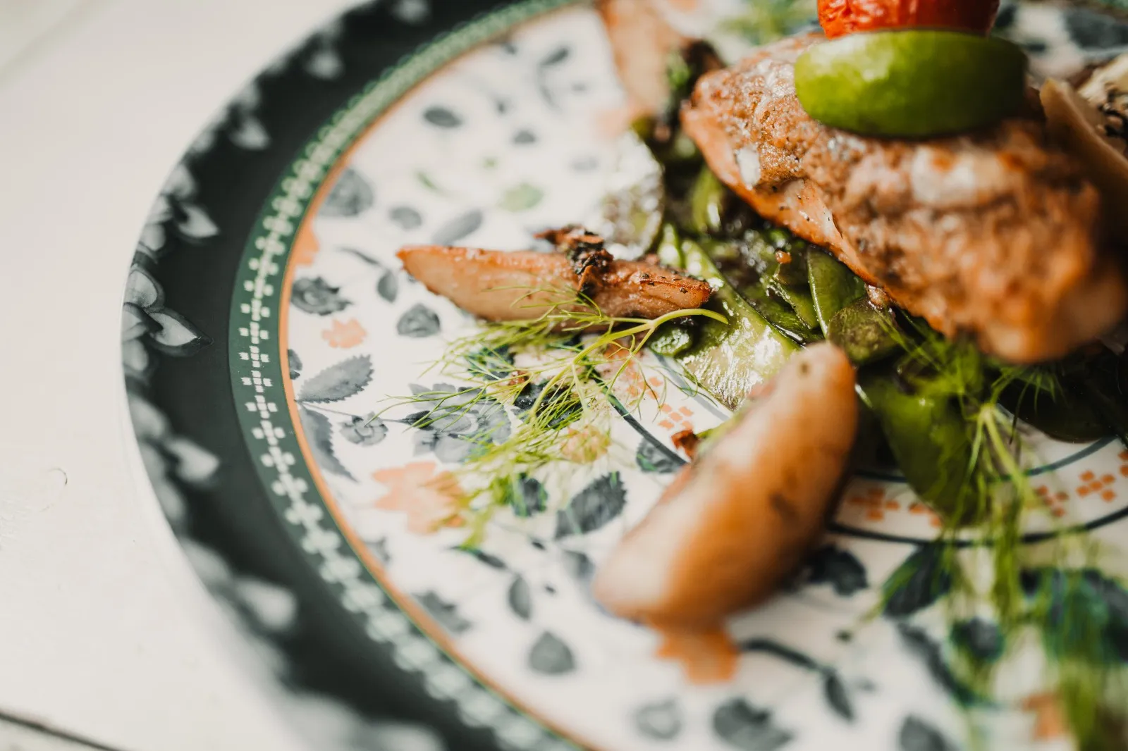 Gebratenes Fischfilet mit Zuckerschoten und Dill auf gemustertem Teller